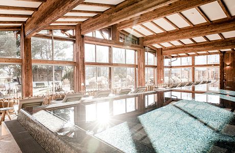 Ein wunderschön gestalteter Wellnessbereich - im alpinen Chic mit viel Altholz. Der Infinity Pool ist mit seinen 17m lang genug für ein paar sportliche Bahnen im Golfresort Das Achental.