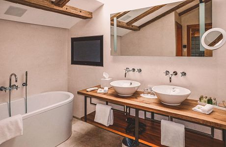 Achental suite - bathroom with TV, bath tub, shower, contemporary facilities in Alpine chic.