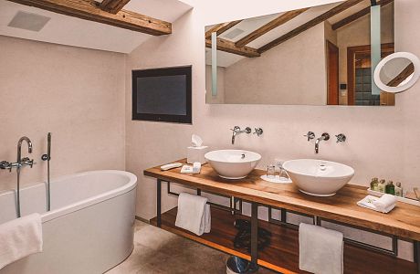 Suite Achental Bad mit TV, Badewanne, Dusche, modern im alpenländischen Chic eingerichtet.
